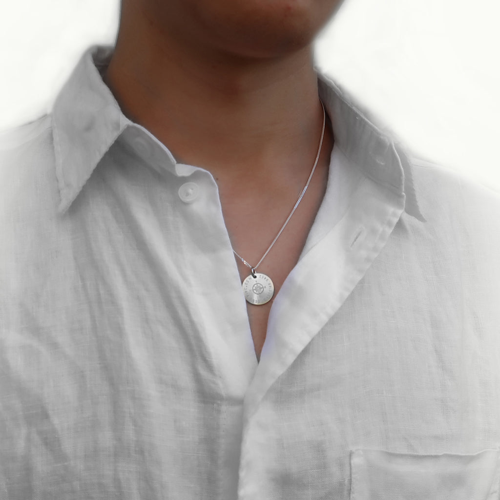 Mann trägt einen Schmuckanhänger aus 925 Silber mit eingravierten Koordinaten