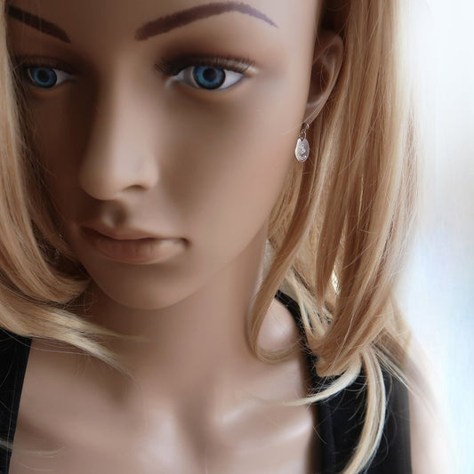 Eine Frau trägt Ohrringe aus 925er Sterlingsilber mit einem eingravierten Namen und zwei Herzen