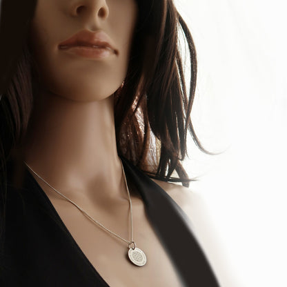 Frau präsentiert Silberkette mit Blume-des-Lebens-Anhänger und individueller Gravur