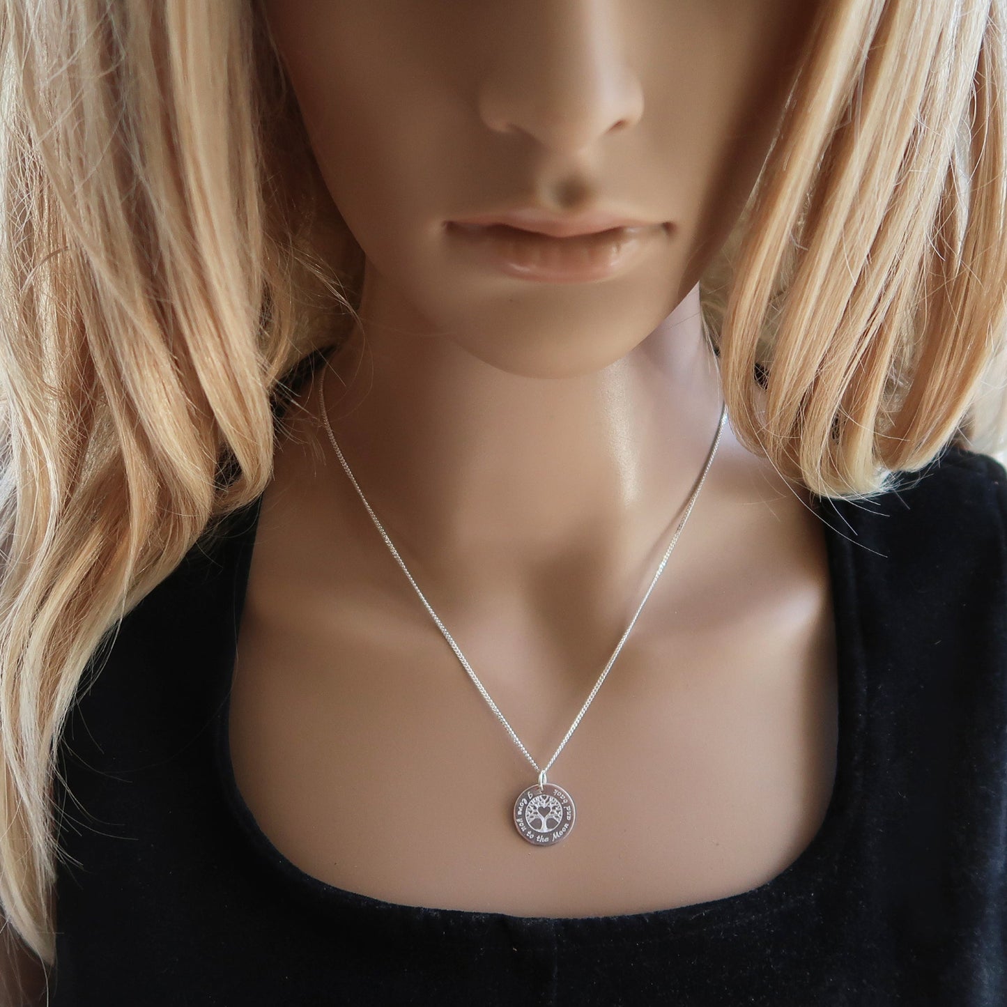 Eine junge Frau trägt Silberkette mit Lebensbaummotiv.