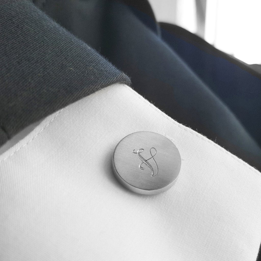 Runder Manschettenknopf mit Buchstaben "V" am Hemd