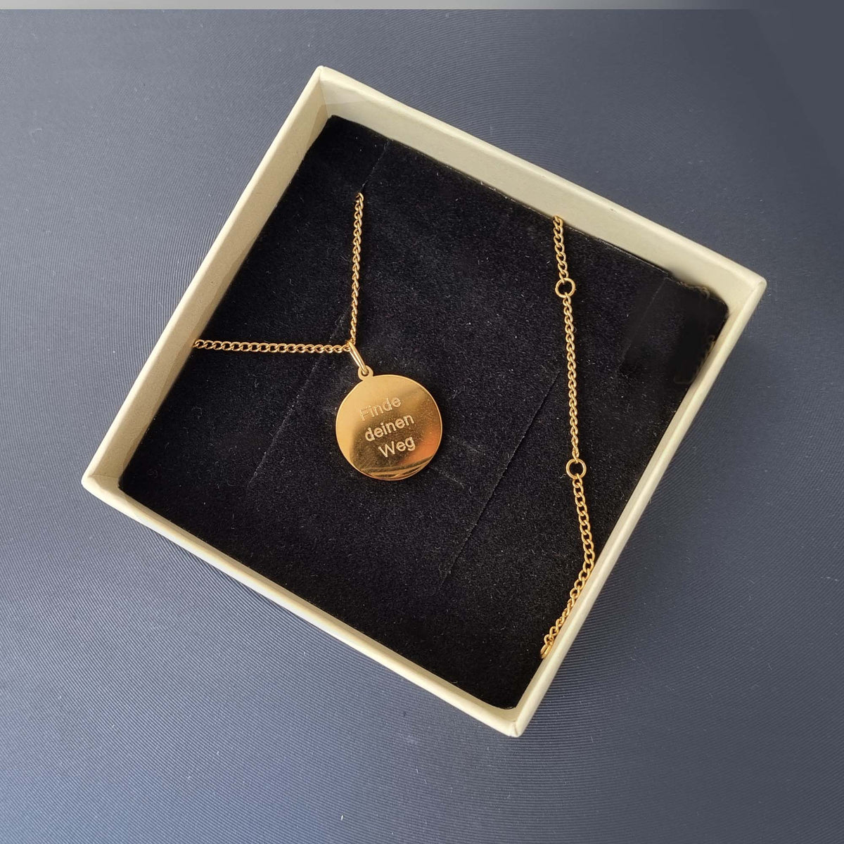 Rückseite einer Kompass-Kette aus vergoldetem Edelstahl mit persönlicher Gravur in einer Geschenkbox