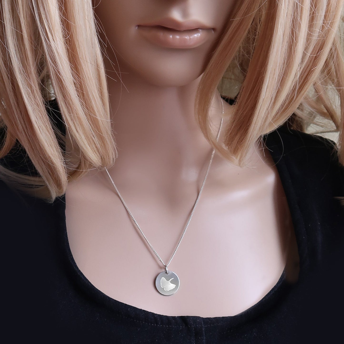 Eine Frau trägt Silberkette mit Gingkomotiv.