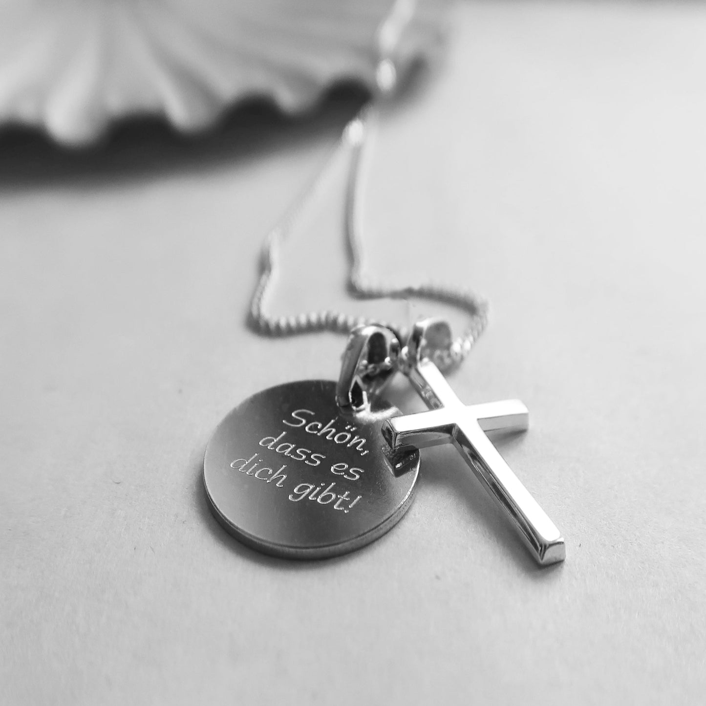 Silberkette mit zwei Kettenanhängern: Kreuzanhänger und runde Gravurplatte mit dem Spruch „Schön, dass es dich gibt!"
