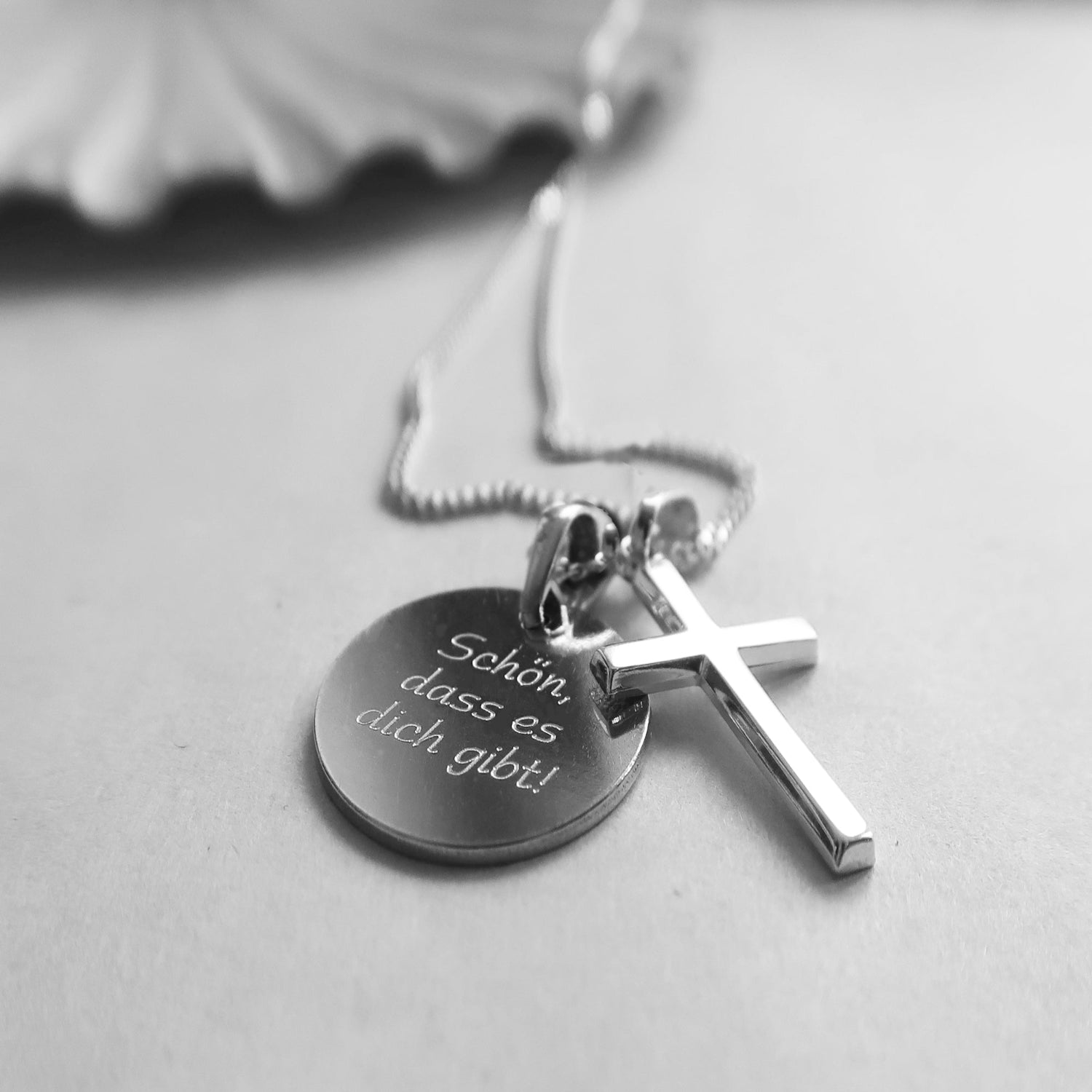Silberkette mit zwei Kettenanhängern: Kreuzanhänger und runde Gravurplatte mit dem Spruch „Schön, dass es dich gibt!"
