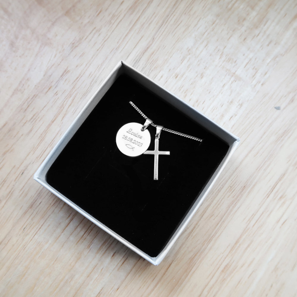 Silberkette mit zwei Anhängern: einem Kreuz und einer runden Gravurplatte, präsentiert in einer Geschenkbox.