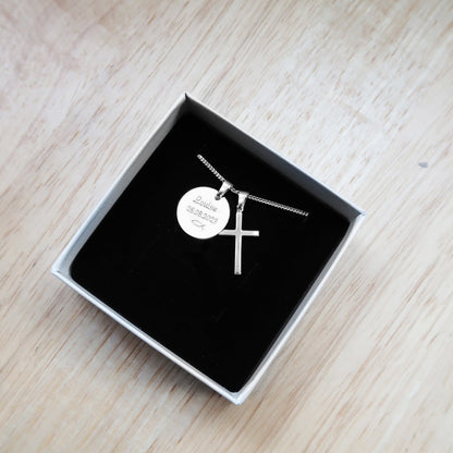 Silberkette mit zwei Anhängern: einem Kreuz und einer runden Gravurplatte, präsentiert in einer Geschenkbox.
