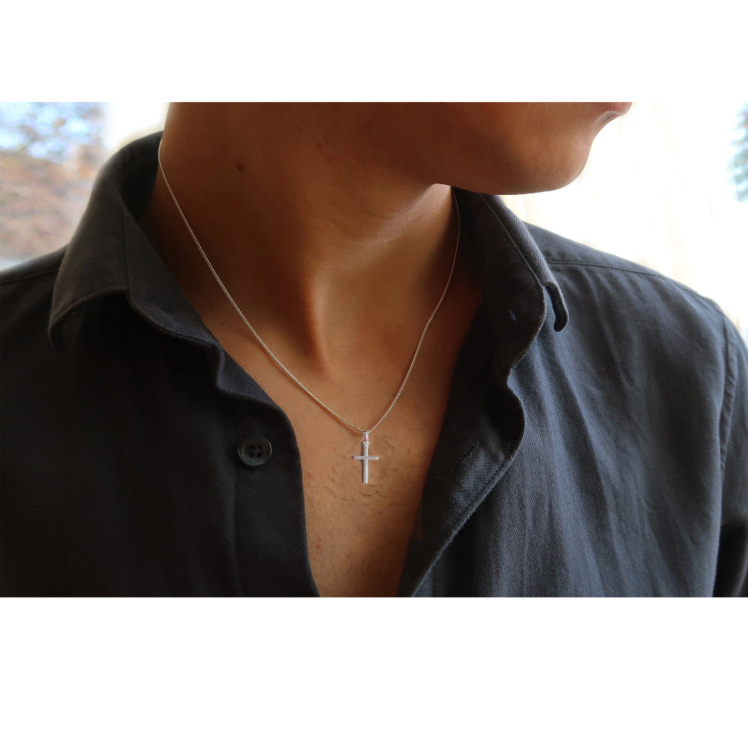 Schlichte Silberkette mit Kreuzanhänger, getragen von einem Mann.