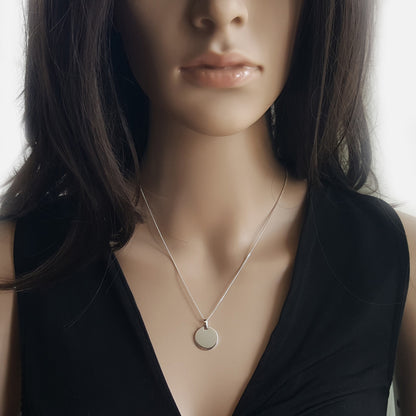 Eine Frau trägt Silberkette mit rundem Anhänger