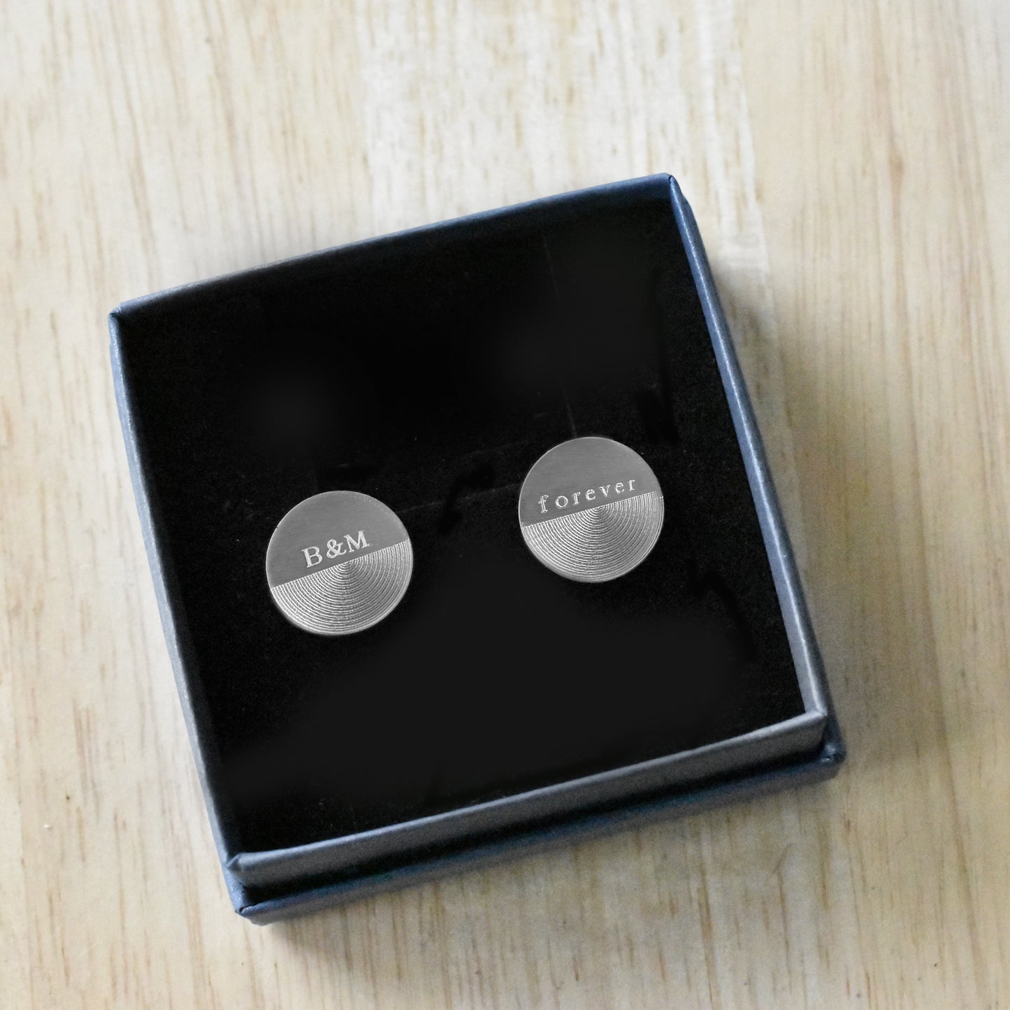 Runde Manschettenknöpfe aus Edelstahl mit matt gebürsteter Oberfläche, personalisierbar mit Wunschgravur, präsentiert in Geschenkbox.