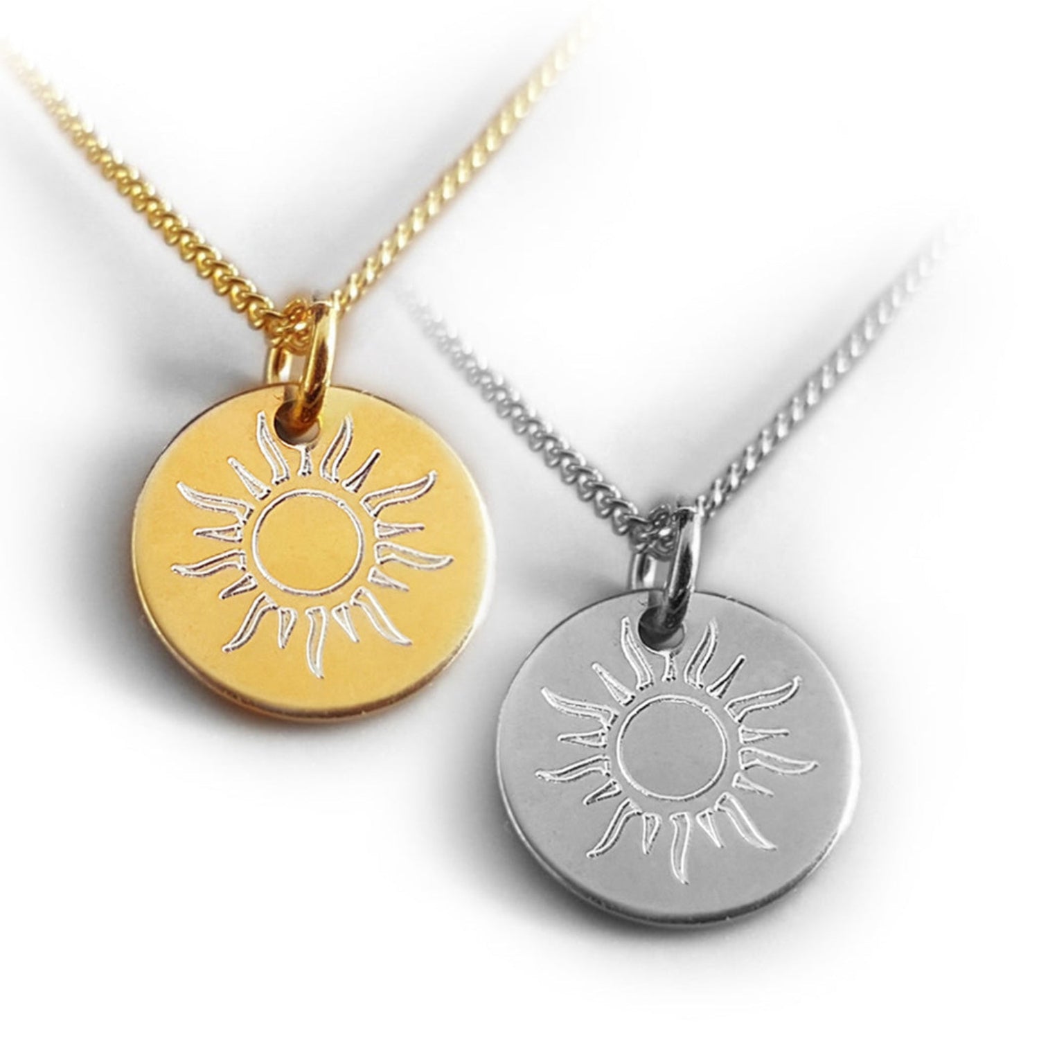 Auf dem Foto sehen Sie zwei Halsketten mit einem kleinen runden Schmuckanhänger mit Sonnenmotiv auf der Vorderseite:  vergoldet und in  Silber 