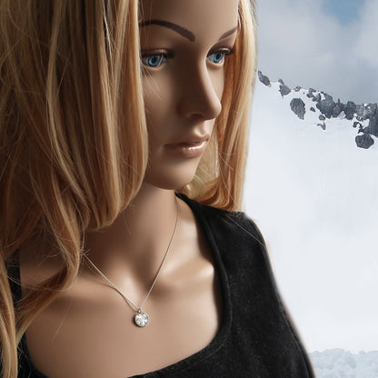 Filigrane Schneeflocken Halskette aus Silber am Hals getragen, vor winterlichem Hintergrund.