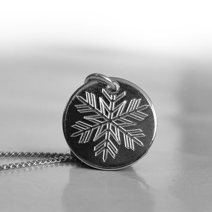 Runder Schneeflocken-Anhänger mit einer rhodinierten Silberkette auf neutralem Hintergrund
