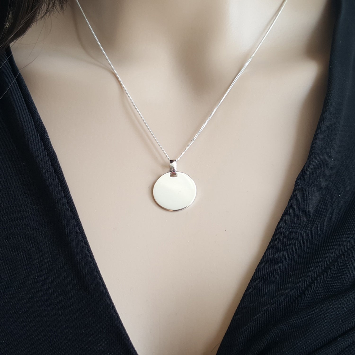 Eine Frau trägt Silberkette mit rundem Anhänger- zoom