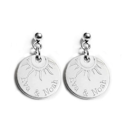 Silberohrringe mit zwei eingravierten Namen und einer halben Sonne.