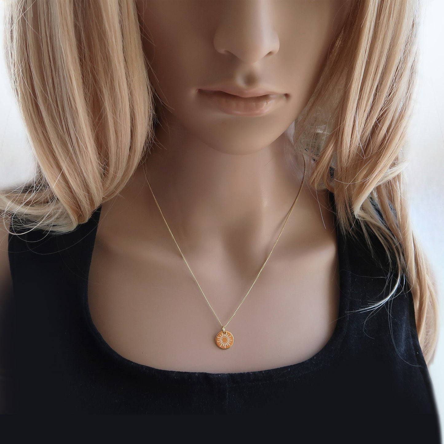 Vergoldete Kette mit Sonnenanhänger am Hals einer Frau