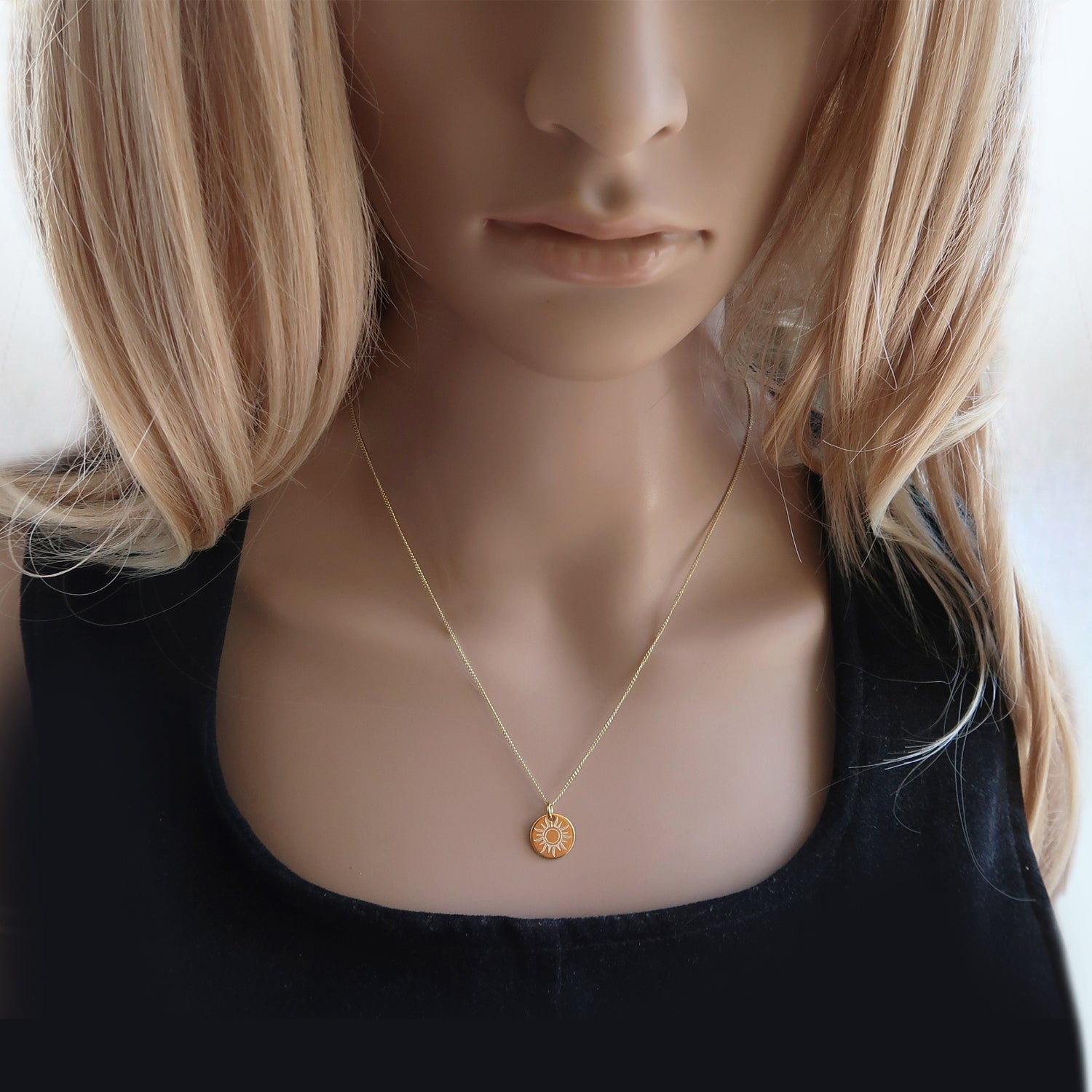 Vergoldete Kette mit Sonnenanhänger am Hals einer Frau