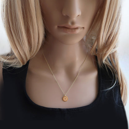 Vergoldete Kette mit Sonnenanhänger am Hals einer Frau