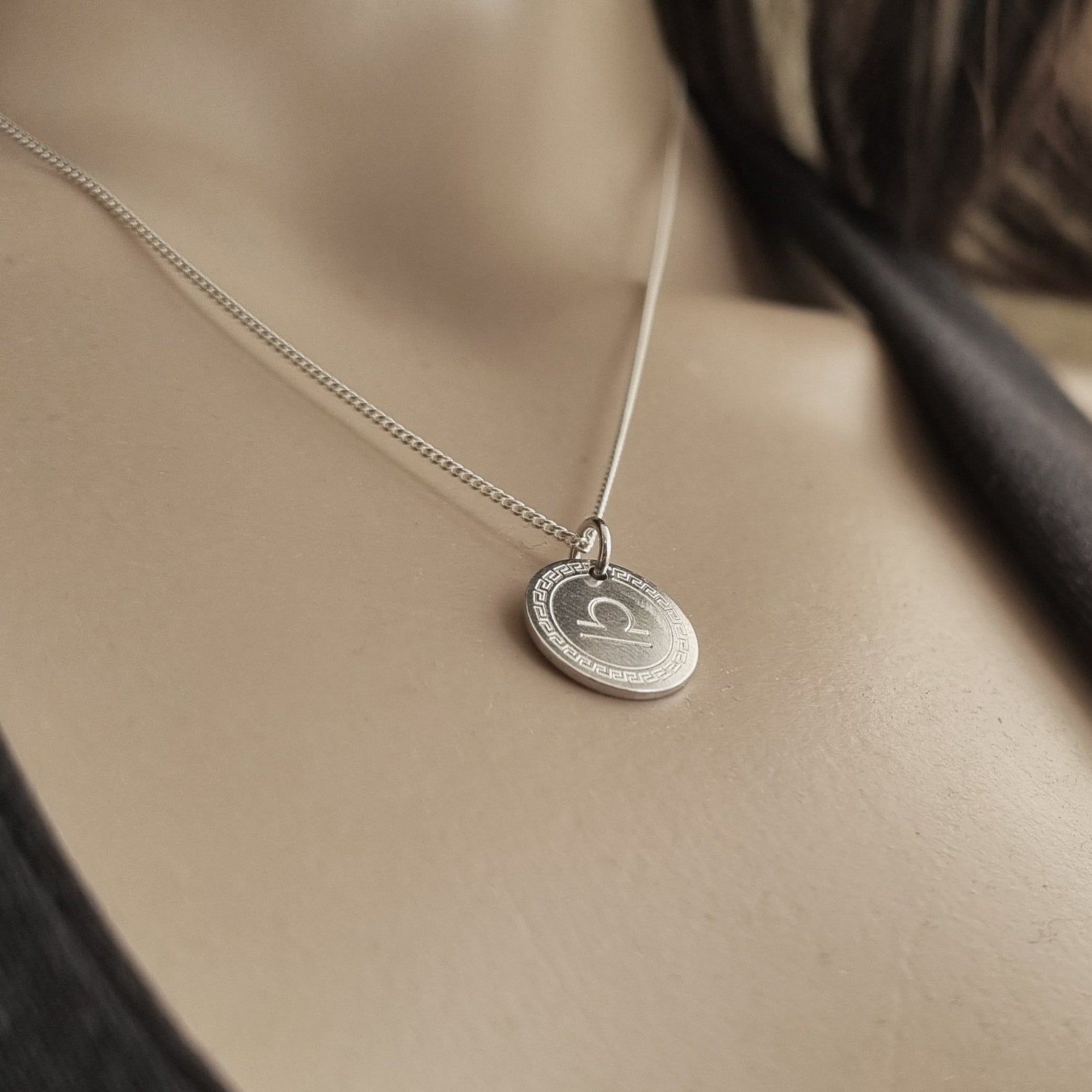 Sternzeichen-Silberanhänger am Hals einer Frau.