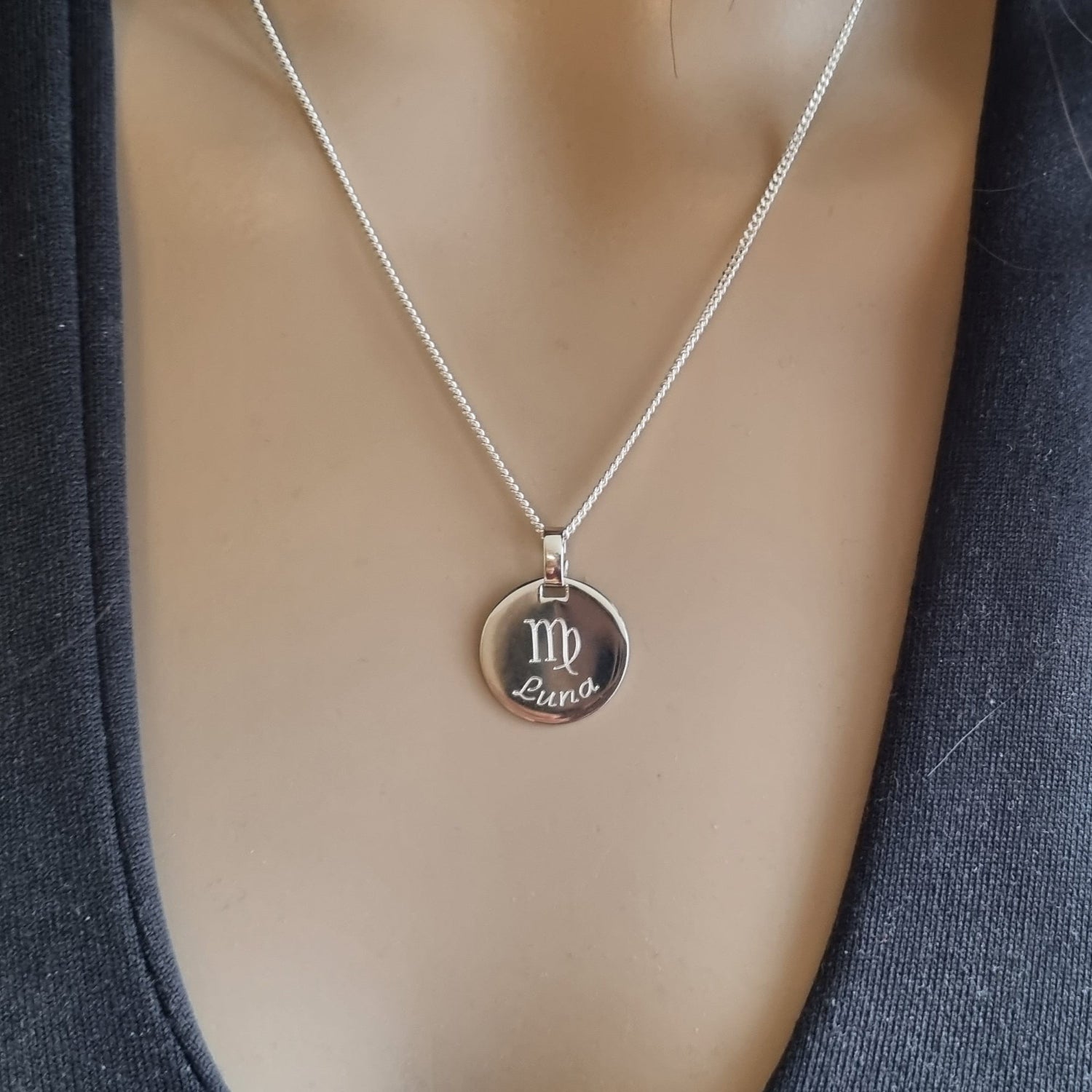 Frau trägt Silberkette mit rundem Anhänger, Sternzeichen und Name – Nahaufnahme