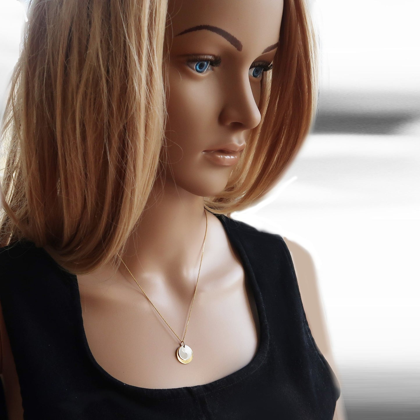 Yin-Yang-Anhänger, getragen am Hals einer Frau.