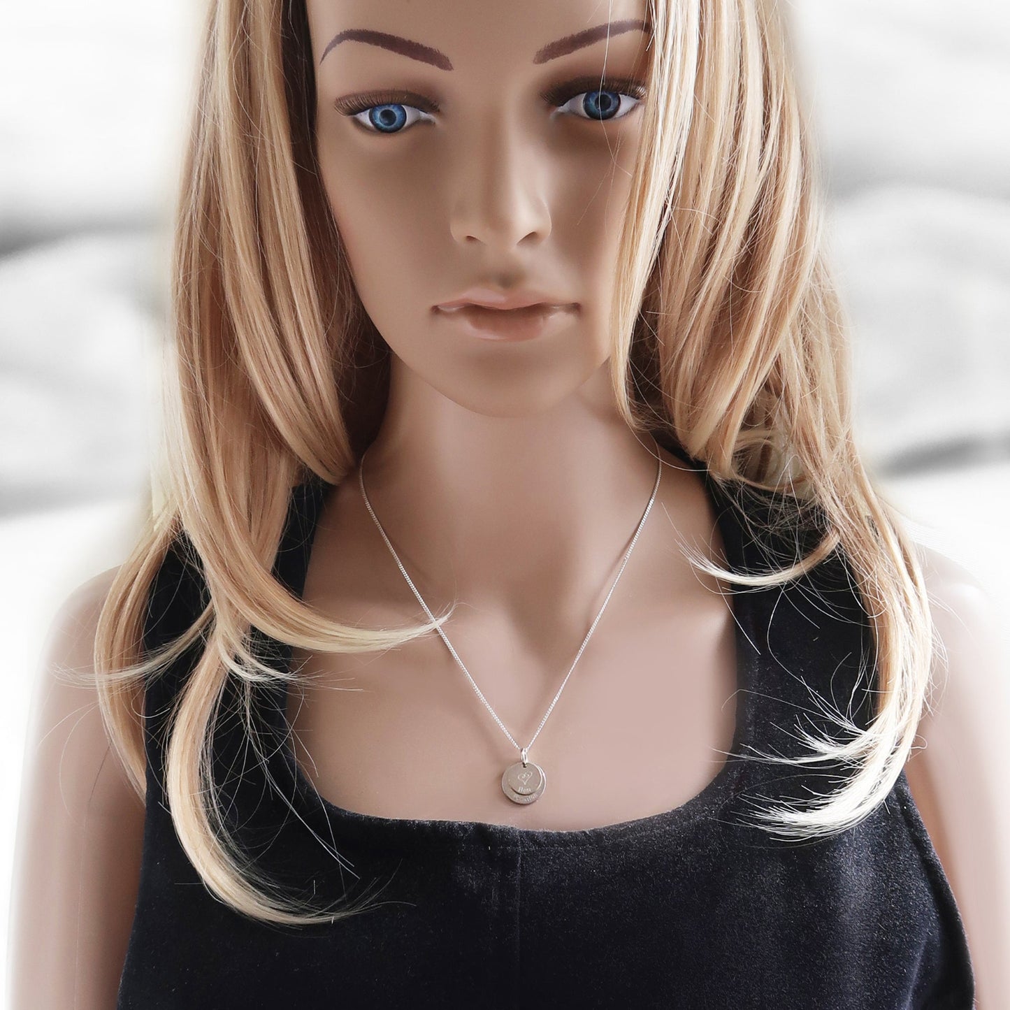 Eine frau trägt eine Halskette mit zwei Anhänger 