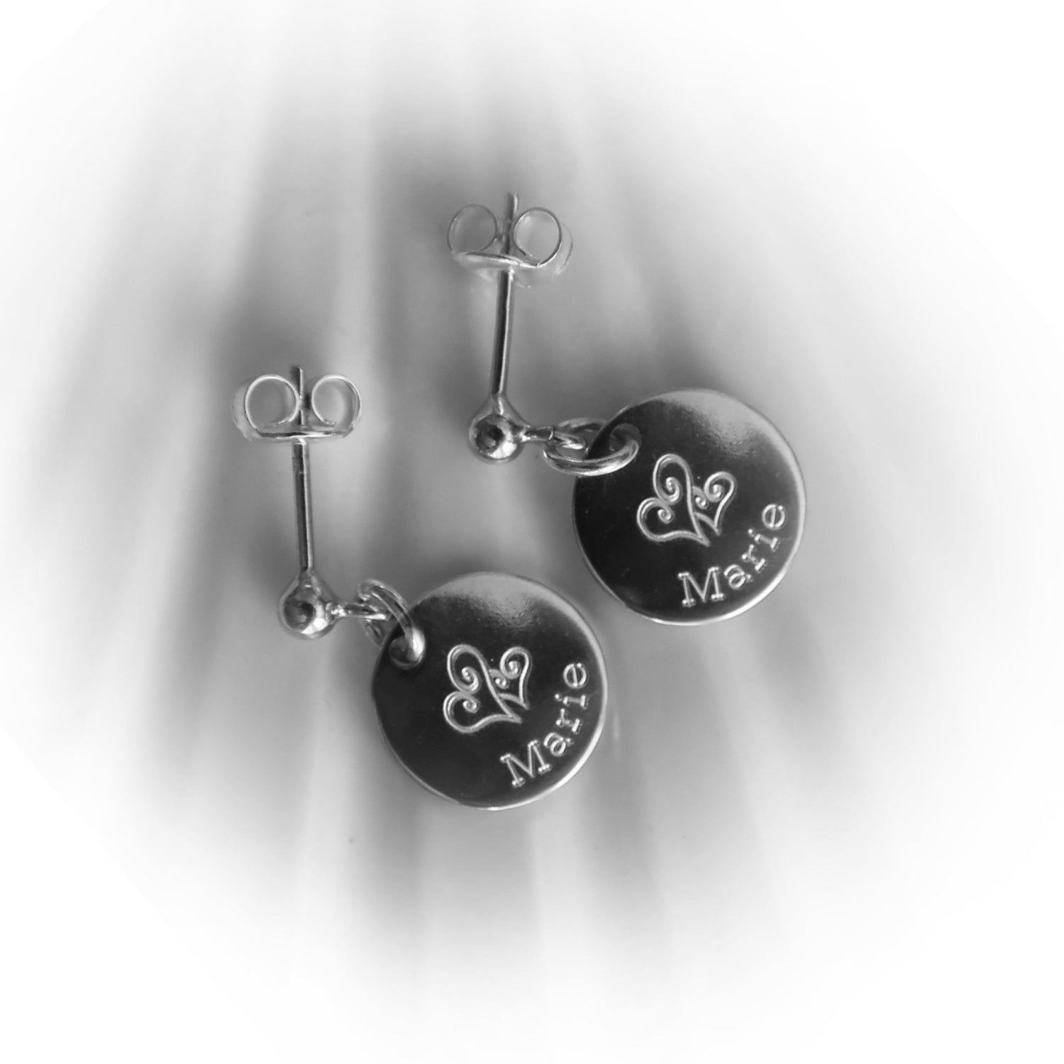 Silberohrringe mit einem eingravierten Namen und zwei Herzen.